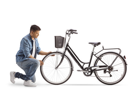 Young man kneeling and checking bicycle wheel isolated on white backgroundの写真素材