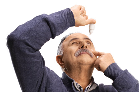 Mature man applying eye drops, health care concept