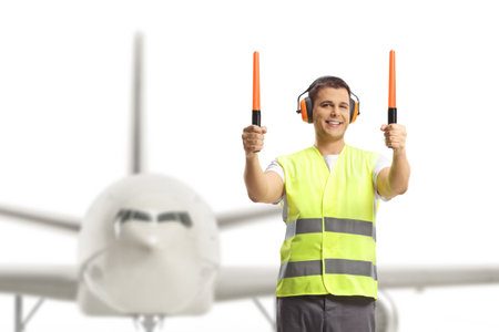 Aircraft marshaller signaling with wands in front of an aircraftの写真素材
