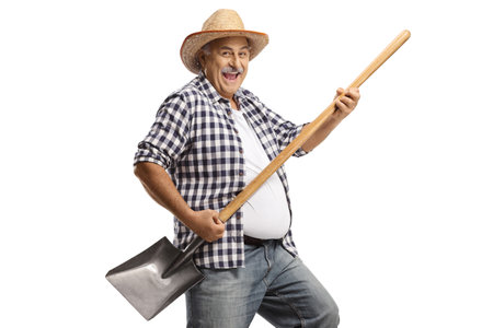 Mature farmer dancing with a shovel isolated on white backgroundの写真素材
