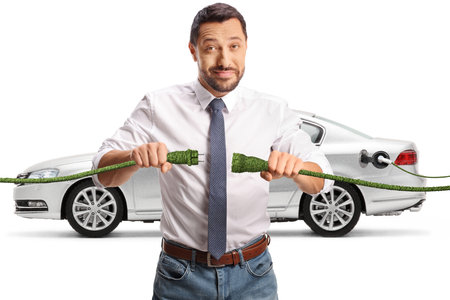 Man holding green cables in front of an electric car isolated on white background, sustainable energy conceptの写真素材