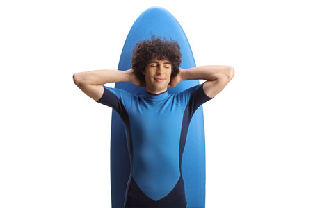 Young man in a wetsuit lying on a surfing board with closed eyes isolated on white background