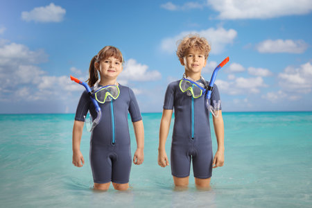 Girl and boy in wetsuits and diving masks standing in the seaの写真素材