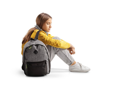 Sad female teenager sitting on the ground and thinking isolated on white backgroundの写真素材