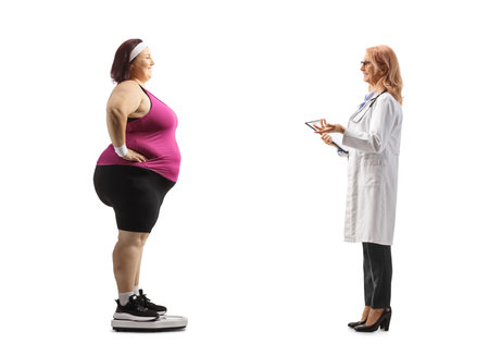 Female doctor talking to a corpulent woman in sportswear on a weight scale isolated on white backgroundの写真素材