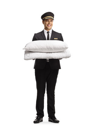 Bellboy in a uniform holding white pillows isolated on white background