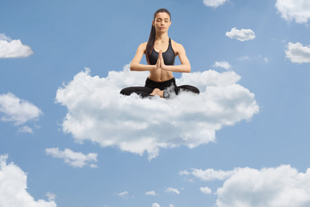 Young female practicing meditation on a cloud up in the skyの写真素材