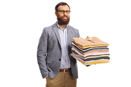 Bearded man holding folded clothes and smiling at camera isolated on a white backgroundの写真素材