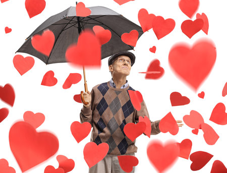 Senior man holding an umbrella under a rain of hearts isolated on white backgroundの写真素材
