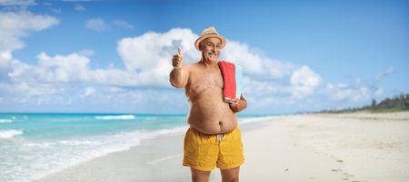 Mature man in swimming shorts posing on a beach in Cuba and gesturing thumbs upの写真素材