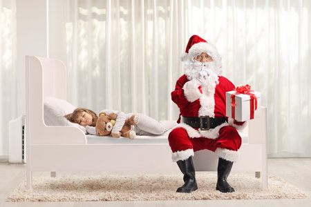 Girl sleeping in her bed and Santa claus delivering a presentの写真素材