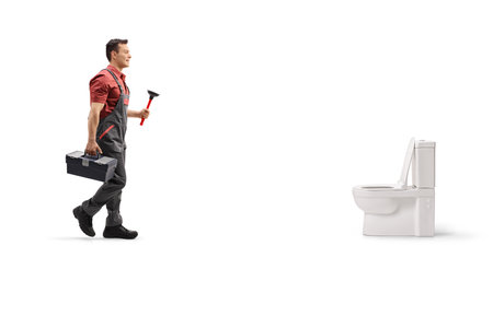 Plumber with a toolbox and a plunger walking towards a toilet seat isolated on white backgroundの写真素材