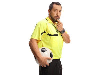 Football referee blowing a whistle and holding a ball isolated on white background