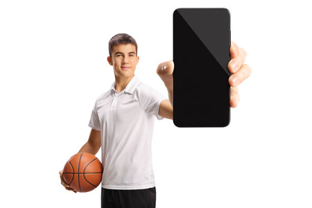 Male teenager holding a basketball and showing a smartphone isolated on white backgroundの写真素材