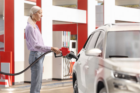 Woman filling a car with gasoline at a petrol station