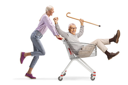 Woman pushing her elderly father inside a shopping cart isolated on white backgroundの写真素材