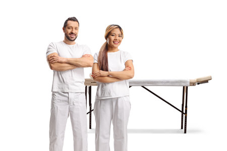 Male and female massage therapists in front of a massage table isolated on white backgroundの写真素材