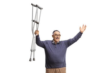 Happy mature man raising crutches isolated on white backgroundの写真素材