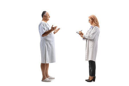 Patient in a hospital gown talking to a female physician isolated on white backgroundの写真素材