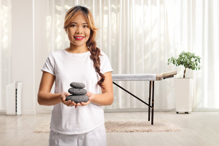 Massage therapist holding stones in a wellness centerの写真素材