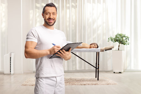 Male therapist writing a document in a massage centerの写真素材