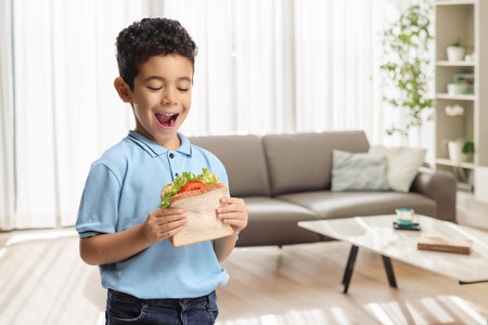 Hungry kid eating a sandwich at homeの写真素材