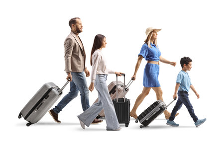 Full length profile shot of a family with a teenage girl and boy walking with suitcases isolated on white backgroundの写真素材