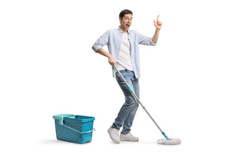Young man cleaning a floor with a mop and dancing isolated on white background