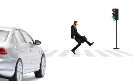 Businessman with a briefcase walking on a zebra crossing in front of a vehicle isolated on white backgroundの写真素材