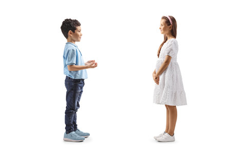 Full length profile shot of a boy having a conversation with a girl in a white dress isolated on white backgroundの写真素材
