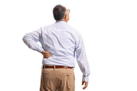 Rear view shot of a mature man in pain holding his spine isolated on white backgroundの写真素材