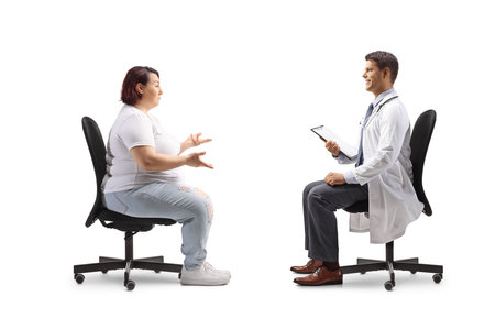 Overweight woman sitting and talking to a male doctor isolated on white backgroundの写真素材