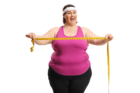 Plus size active woman holding a measure tape and smiling isolated on white backgroundの写真素材