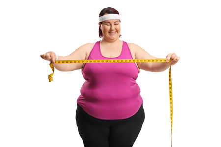Plus size active woman holding a measure tape isolated on white backgroundの写真素材