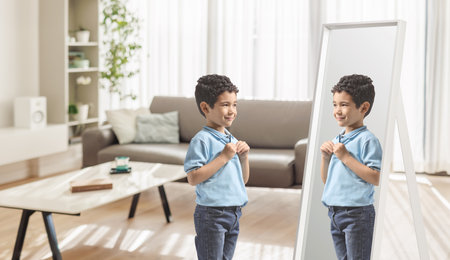 Kid putting on a t-shirt and looking at a mirrorの写真素材