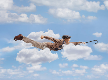 Senior man flying in the sky and holding a walking caneの写真素材