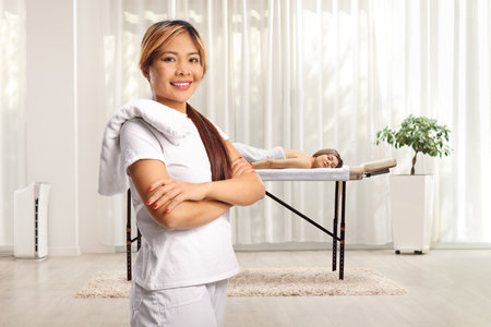 Femal asian therapist with towel on her shoulder at a massage centerの写真素材