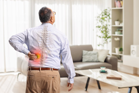 Rear view shot of a mature man holding his spine with red inflamed spotの写真素材