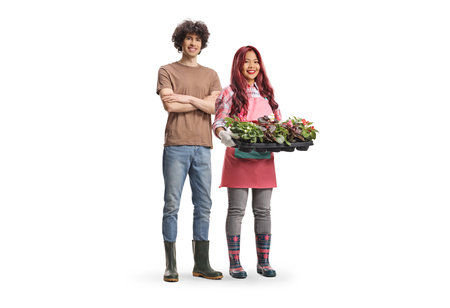 Full length portrait of a young male and female gardeners holding flower pots isolated on white backgroundの写真素材