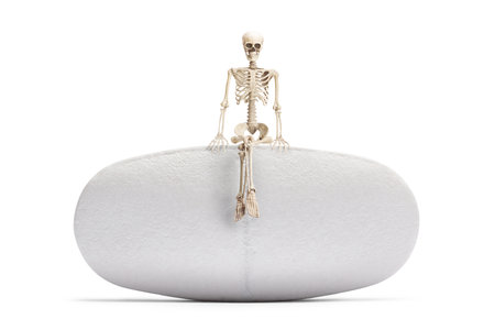 Human skeleton seated on a pill isolated on white backgroundの写真素材
