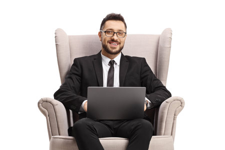 Businessman sitting in an armchair with a laptop computer  isolatedon white backgroundの写真素材