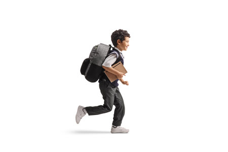 Asian schoolboy in a uniform running and holding a book isolated on white backgroundの写真素材