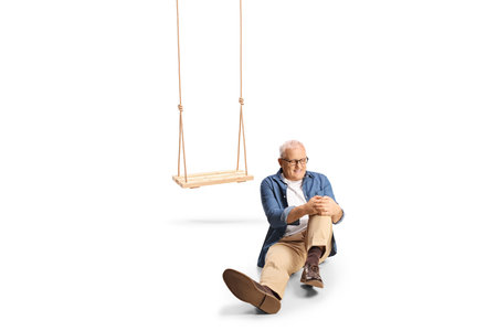 Man with an injured knee falling from a swing and sitting on the ground isolated on white backgrounddの写真素材