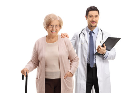 Doctor and an elderly female patient with a walking cane posing isolated on white backgroundの写真素材