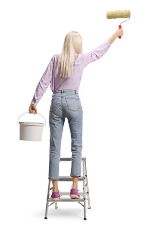 Rear view shot of a woman on a ladder painting a wall isolated on white backgroundの写真素材