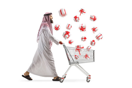 Full length profile shot of a man in middle eastern clothes pushing a shopping cart with flying presents isolated on white backgroundの写真素材