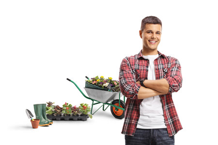 Male gardener with flowers and a wheelbarrow posing with crossed arms isolated on a white backgroundの写真素材