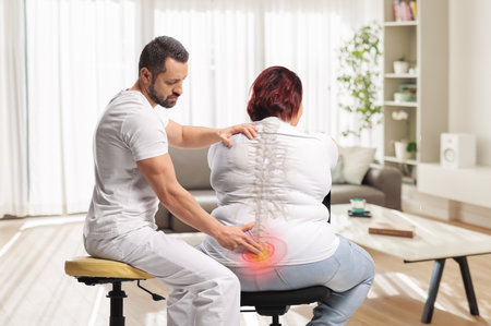 Chiropractor treating a woman with painful spot in the backの写真素材