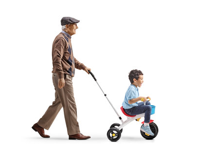 Elderly man pushing boy on a tricycle isolated on white backgroundの写真素材