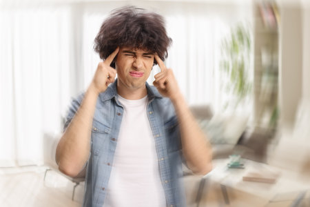 Young man at home suffering from headache and fatigueの写真素材